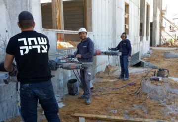 עובדי בעבודת קידוח בקיר בטון באתר בנייה