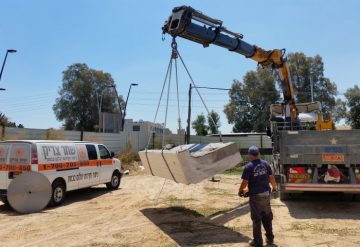 יחידת בטון לאחר ניסור תלויה על מנוף לצד רכב עבודה של החברה