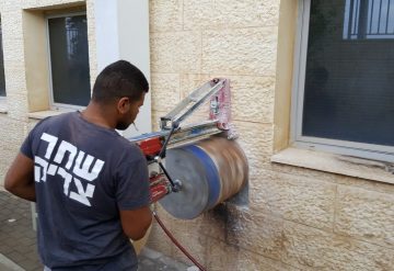 עובד של חברת שחר צדיק מבצע קידוח בקיר בטון