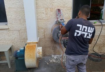 עובד של חברת שחר צדיק מבצע קידוח בקיר בטון